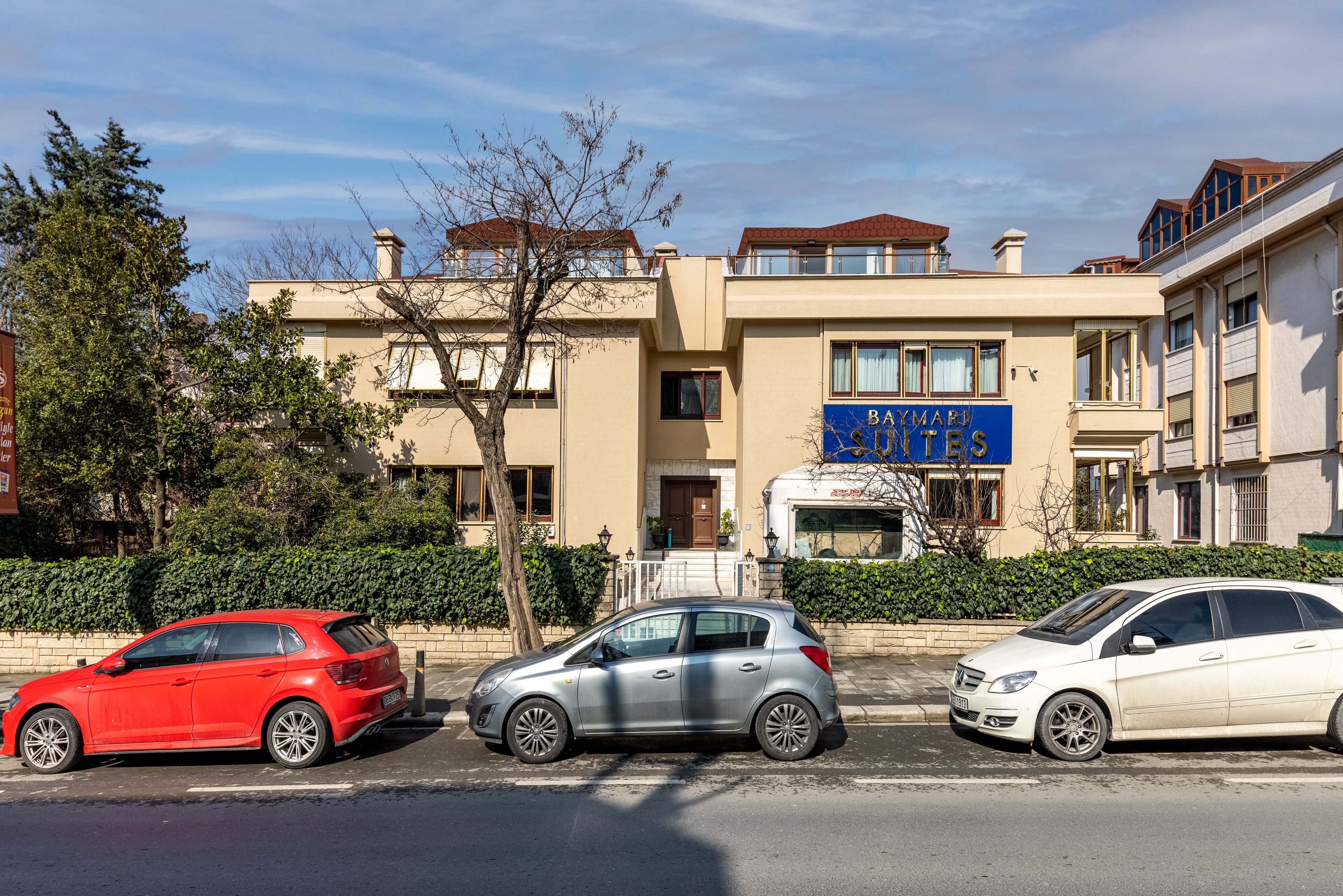 Three cars parked in front of a building with a sign that reads "BAYMAR STUDIO".