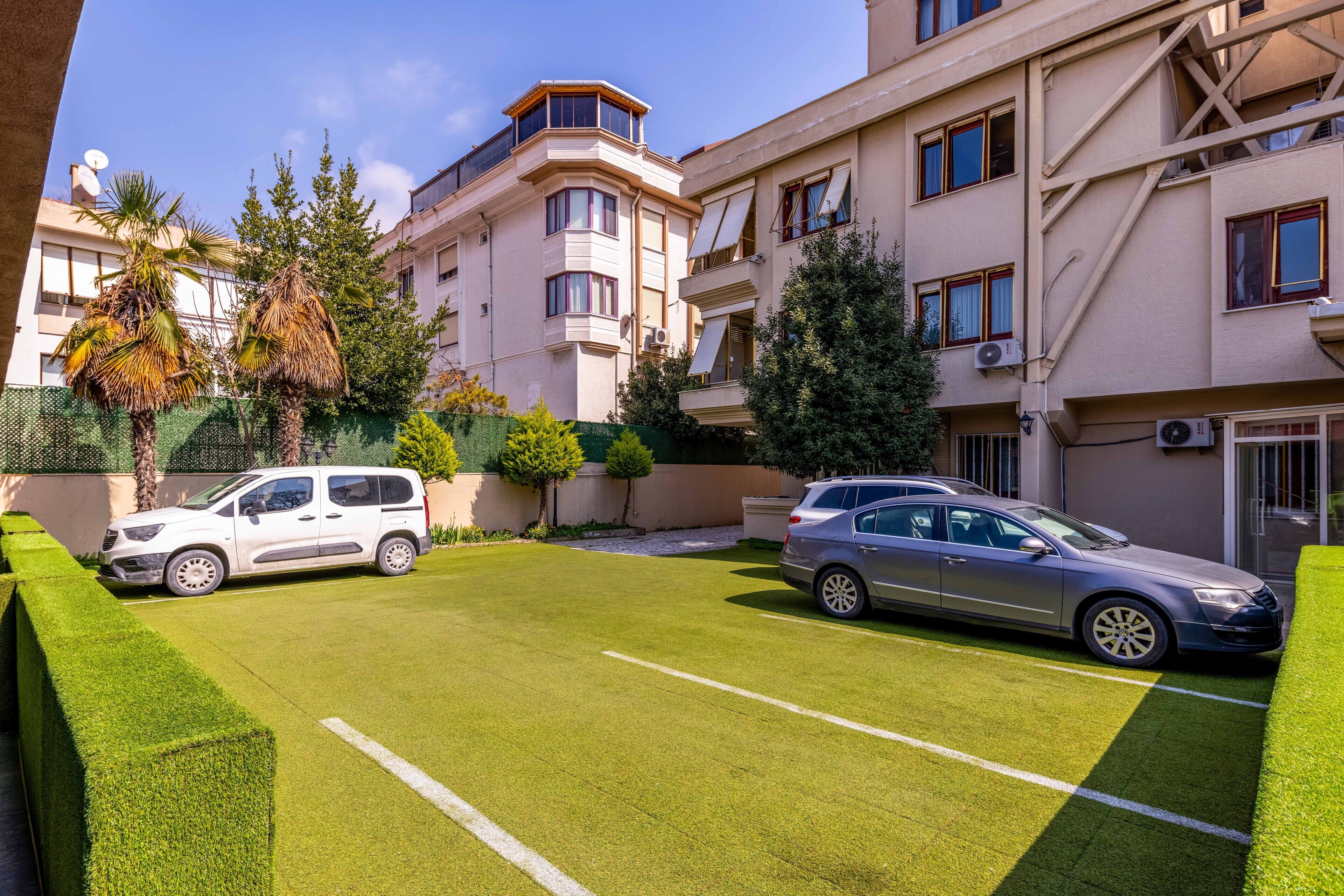 Un edificio residencial con dos coches estacionados en una entrada de vehículos bien cuidada.