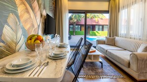 Una sala de estar moderna con comedor, un sofá y vista a la piscina.