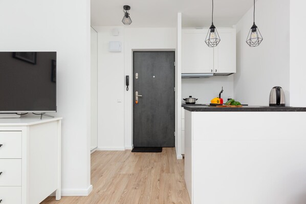 A modern kitchen with white cabinets, a black countertop, and a door leading to another room.