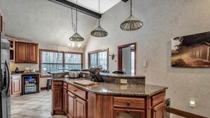 Una cocina amplia con armarios de madera, encimeras de granito e iluminación colgante.