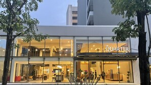A hotel named 'QUARTER' with a modern design, featuring a glass facade, outdoor seating area, and a visible staircase leading to the entrance.