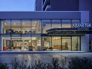 Hotel met een modern design, met een glazen gevel, een receptie en een zichtbaar buitenzitgedeelte.