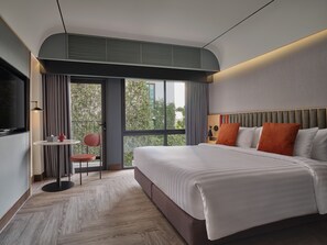 A modern hotel room with a large bed, a small table with a chair, a TV, and a balcony with curtains. - The Quarter Onnut by UHG (Bangkok)