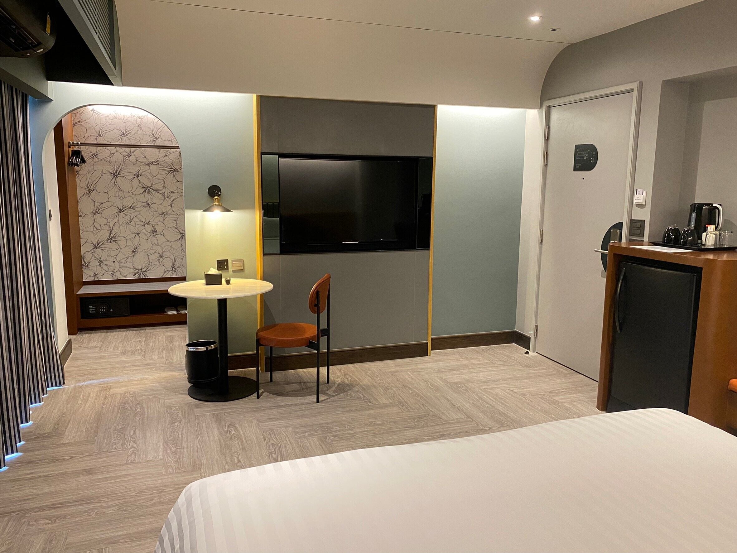 A hotel room with a bed, a desk with a chair, a TV, and a coffee machine.