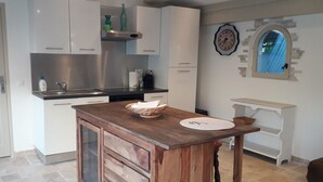 A kitchen with white cabinets, a wooden island, and a clock on the wall.