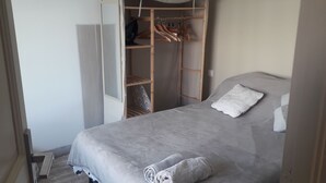 A bedroom with a bed, a wardrobe, and a small closet.