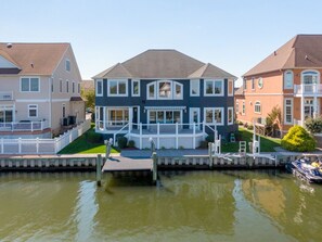 A waterfront property with a large house featuring a covered porch and a dock.