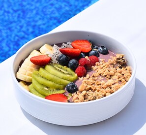 A bowl of fruit and granola with a blue background. - Al Maya Island & Resort (Abu Dhabi)
