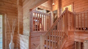 Una scala in legno con ringhiera, un vaso con rami e una porta che dà sull'esterno.