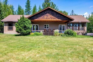 Situated in a serene natural setting, this lodge offers a cozy atmosphere with a covered porch area perfect for relaxation.