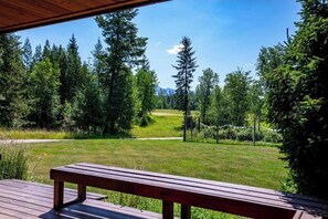 Enjoy a serene view of the surrounding landscape from this deck, overlooking dense trees and a distant mountain range.