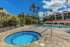 Un espace piscine d’hôtel comprenant plusieurs piscines, des palmiers et un ciel d’un bleu éclatant.