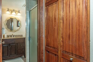 Une salle de bain avec une porte en bois, un meuble-lavabo avec un miroir et un espace douche.