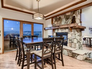 A spacious dining area with a stone fireplace, large windows, and a view of the outdoors.