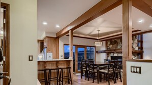 A spacious kitchen with wooden beams, a dining area with a large table and chairs, and a stone accent wall. - Moose on the Loose: Private Hot Tub, Mountain Views, Quick Ski Access (Breckenridge)