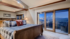 A bedroom with a large bed, a view of the city through a sliding glass door, and a balcony with a view of the mountains. - Moose on the Loose: Private Hot Tub, Mountain Views, Quick Ski Access (Breckenridge)