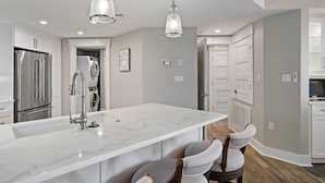 Una cucina moderna con una grande isola, elettrodomestici in acciaio inossidabile e illuminazione a sospensione.