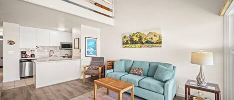 A modern living room with a sofa, coffee table, and a painting on the wall.
