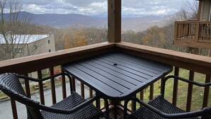 Un balcon avec une table et des chaises, donnant sur un paysage montagneux.