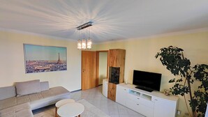 A modern living room with a sofa, a coffee table, a TV, and a large plant. - Idyllic vacation apartment near the Ilz for 3 people (Hutthurm)