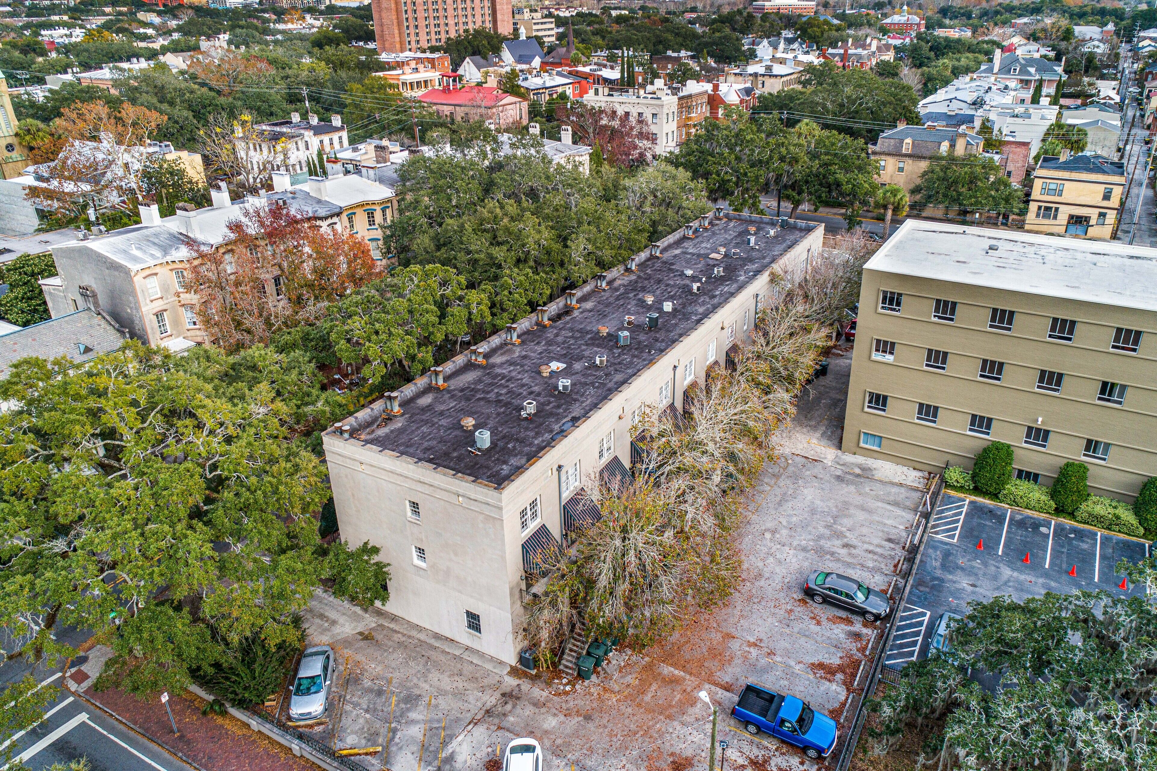 An aerial view of a building with a flat roof, surrounded by trees and other buildings.