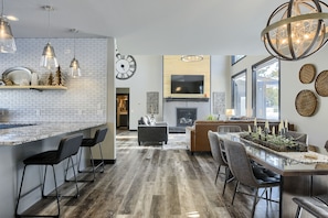 A modern kitchen with a white brick backsplash, bar stools, and pendant lighting.