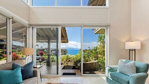 Un salon spacieux doté d’une grande porte-fenêtre coulissante donnant sur un balcon avec vue sur l’océan.