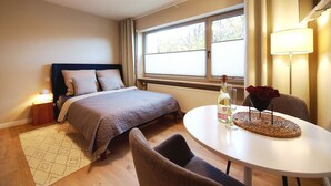 Ein Schlafzimmer mit Bett, Nachttisch, Lampe und einem Essbereich mit Tisch und Stühlen.