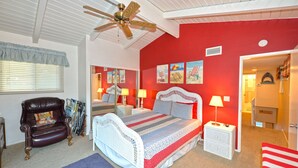 Une chambre à coucher avec un lit, une chaise, un ventilateur de plafond et un mur rouge.