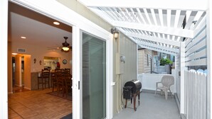 Un patio couvert équipé d’un barbecue, de chaises et offrant une vue sur le jardin arrière.