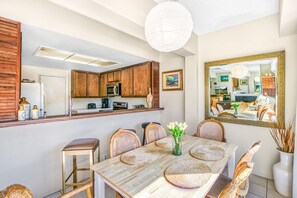 A dining area with a wooden table, woven placemats, wicker chairs, and a vase of flowers. - C63: 3BD CONDO + Balcony + 2 bathrooms (Avalon)