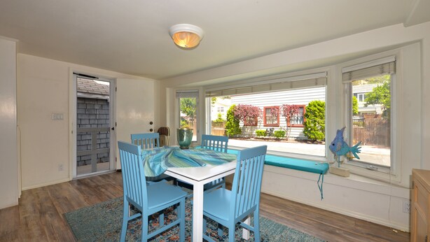A dining area with a table and chairs, a window with a view of the backyard, and a ceiling light fixture. - 337CA: Charming 2-bdr Avalon cottage on the flats (Avalon)