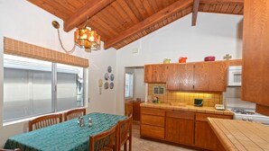 A kitchen with wooden cabinets, a dining table with chairs, and a window with blinds. - 337CA: Charming 2-bdr Avalon cottage on the flats (Avalon)