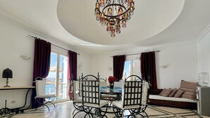 Een eethoek met een kroonluchter, een tafel met stoelen en een bank met gestreepte kussens.