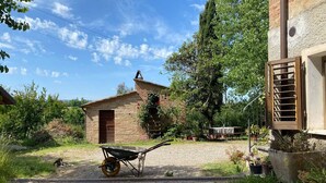 Edifici de pedra rústic amb una porta de fusta i una petita escala que mena a un altell.
