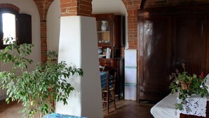 Una habitació amb arcs de maó, un armari de fusta, una taula amb cadires i un frigorífic.