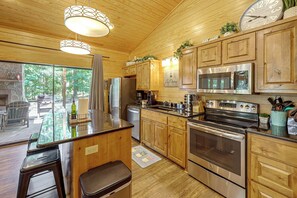 A modern kitchen with wooden cabinets, stainless steel appliances, and a central island. - Hot Tub, Fire Pit, Forest Views! Broken Bow Cabin (Broken Bow)
