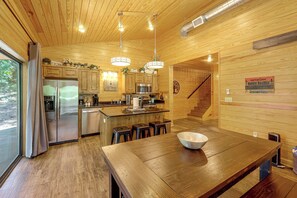 A modern kitchen with wooden paneling, stainless steel appliances, and a central island with stools.
