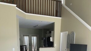 A spacious living room with a large sectional sofa, a flat-screen TV, and a staircase leading to an upper level. - Cozy, Stylish Garden Home (Dothan)
