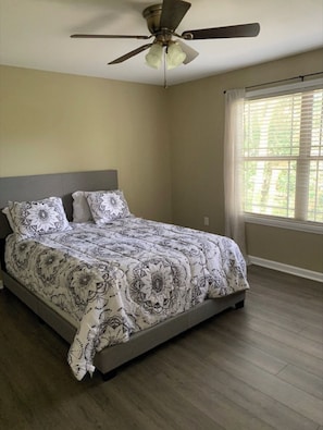 A bedroom with a bed, a ceiling fan, and a window with blinds. - Cozy, Stylish Garden Home (Dothan)