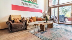 Ein Wohnzimmer mit einer Couch, einem Couchtisch und einem Teppich. An der Wand ist ein Bär zu sehen, sowie der Schriftzug 'California Republic'.