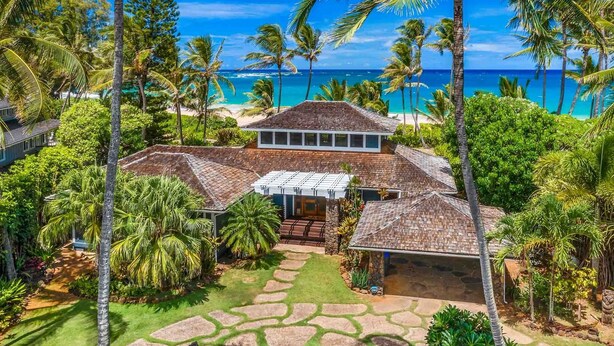 A beachfront property with a large house, a covered patio, and a stone pathway.