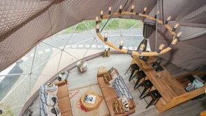Een ruim, modern interieur met een ronde zithoek, een houten bar en een uniek plafondontwerp.