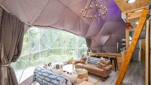 Een gezellig interieur met een groot raam, een houten trap en een keukenhoek.