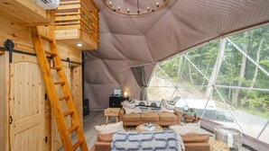 Een gezellig houten interieur met een groot raam en een geometrisch plafond.