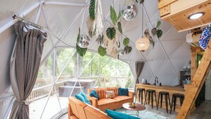A cozy interior with a sofa set, hanging plants, and a bar area. - ✨🥂 Glamping Dome with Full Bath, Kitchen, Fire Pit, & Grill (Cosby)