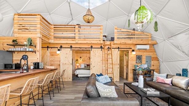 Un intérieur chaleureux avec un bar en bois, un coin salon et une chambre à coucher située en mezzanine.