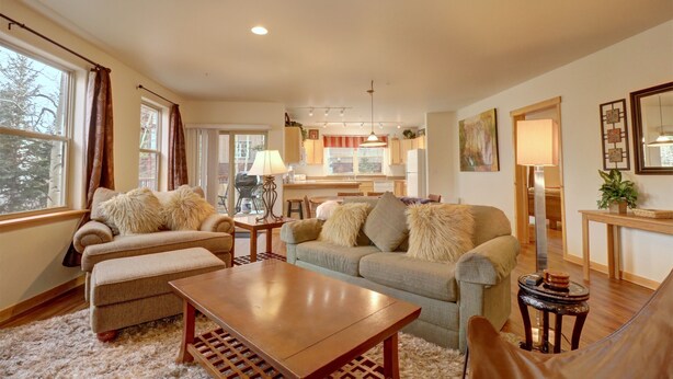 A cozy living room with a sofa, armchair, and coffee table. There is a dining area with a table and chairs. - 101 Streamside Lane 2 Bedroom Condo by RedAwning (Frisco)