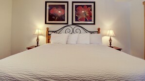 A neatly made bed with white linens, two bedside lamps, and two framed floral paintings on the wall. - 101 Streamside Lane 2 Bedroom Condo by RedAwning (Frisco)